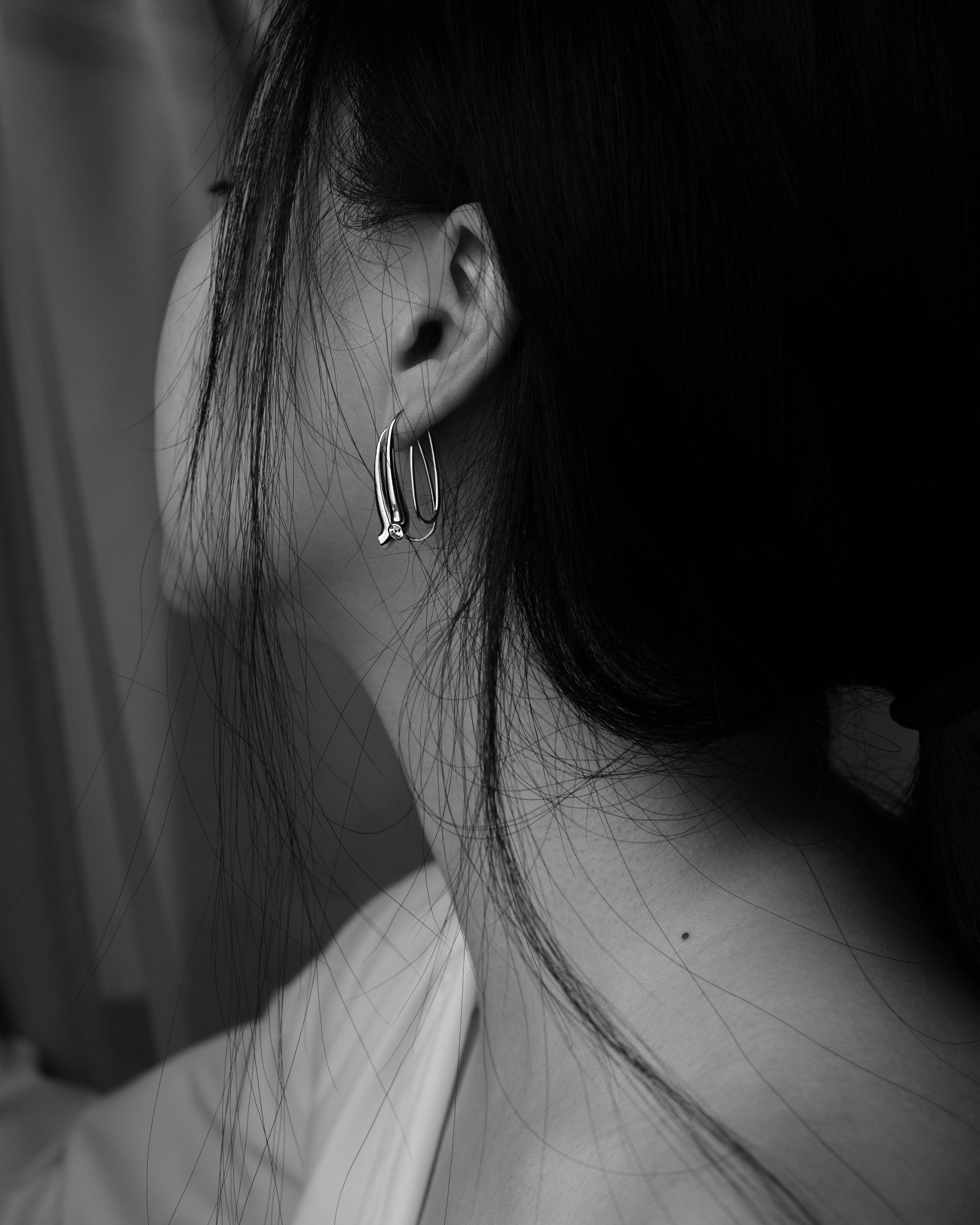 woman with silver earring grayscale photo